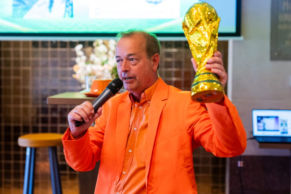 Leon van der Wilk in Oranje-colbert met de WK-beker tijdens de WK 2026 quiz